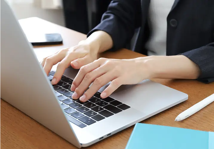 ビジネスパーソンがノートパソコンで文字を入力している手元のクローズアップ
