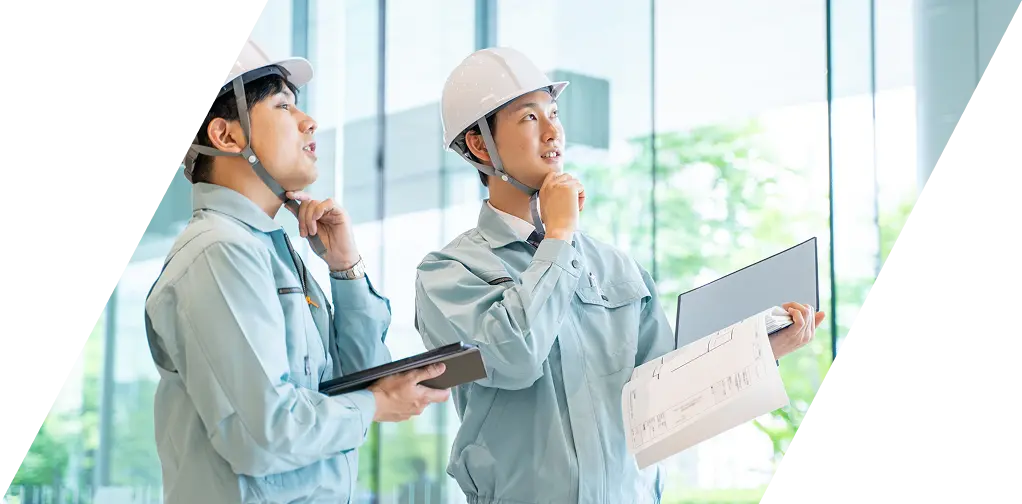 明るいガラス張りの空間で建築計画を進める建設作業員の姿