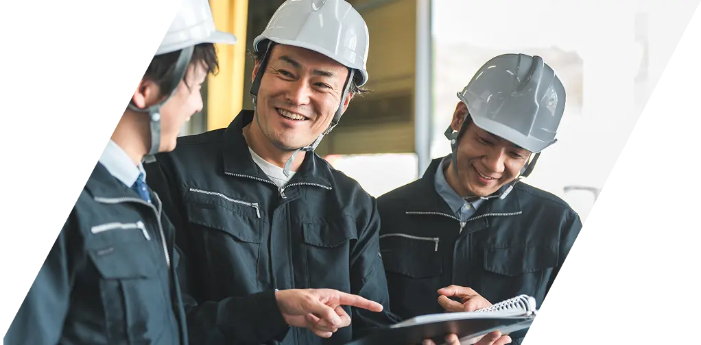 作業服とヘルメットを着用し、和やかな雰囲気で仕事をするチーム