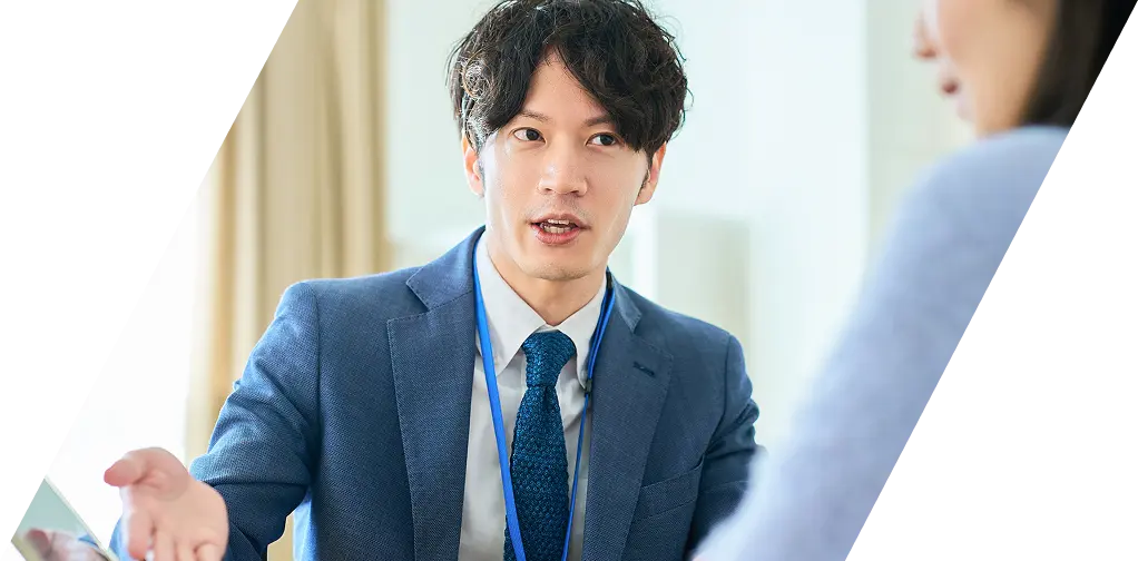 IDカードを首から下げて顧客に提案を行う営業担当者の様子