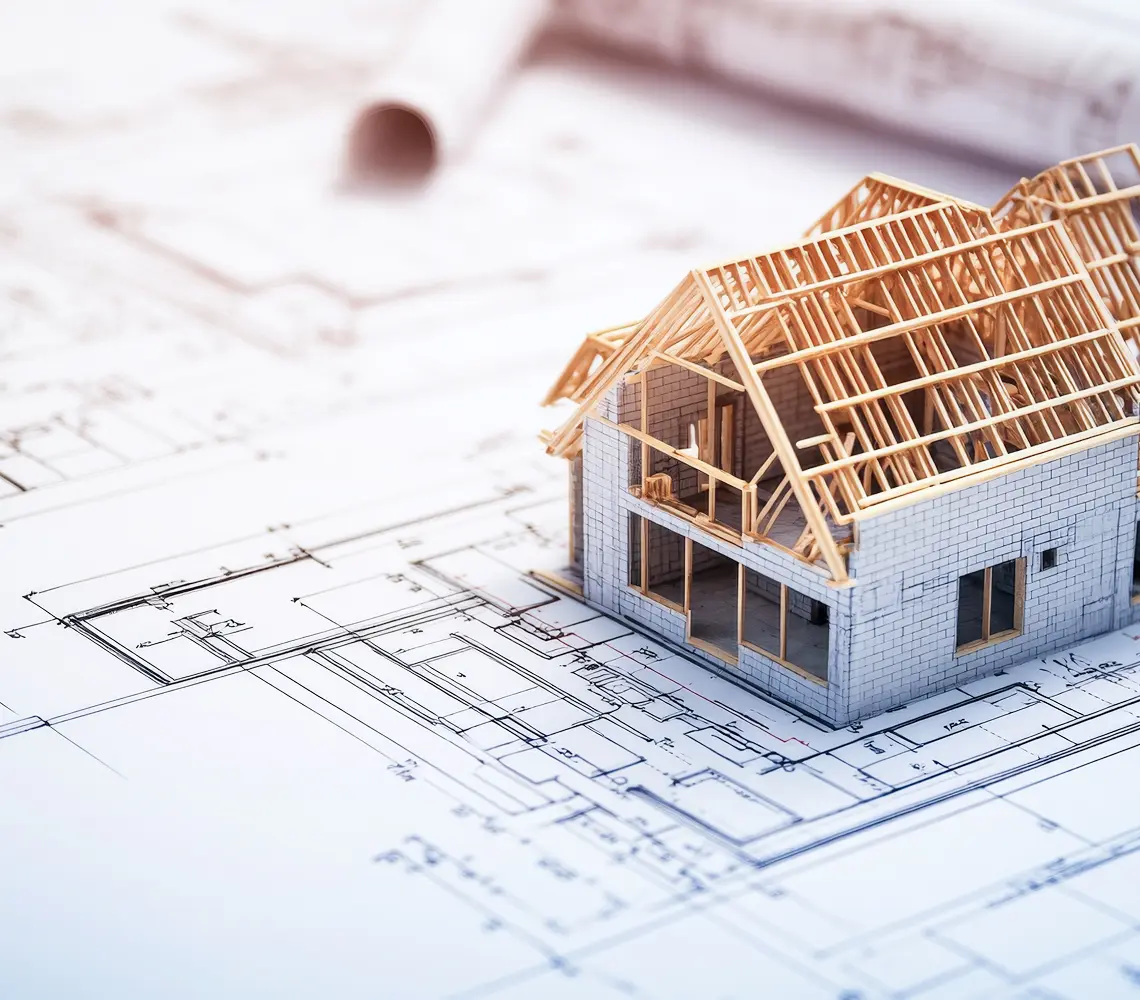 設計図の上に木造住宅の模型が置かれており、建築計画を示すイメージ